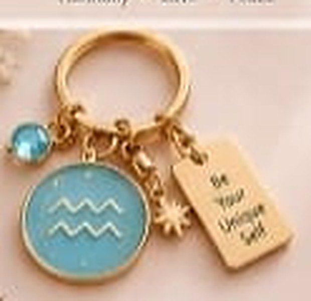 Aquarius zodiac keychain with a gold ring, enamel sign disc, crystal, star charm and tag reading Be Your Unique Self