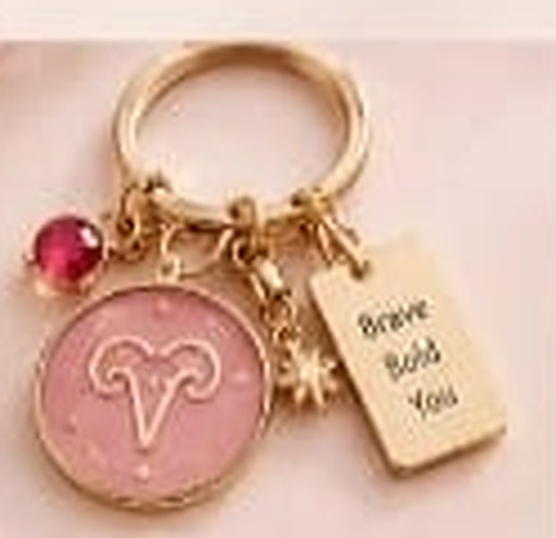 Aries zodiac keychain with a gold ring, enamel sign disc, crystal, star charm and tag reading Brave Bold You