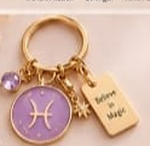 Pisces zodiac keychain with a gold ring, enamel sign disc, crystal, star charm and tag reading Believe in Magic